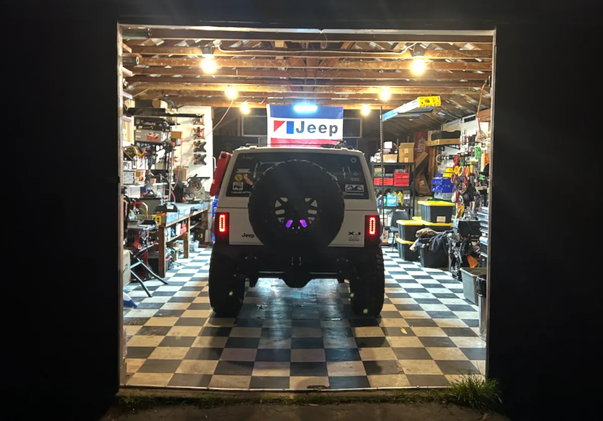 The XJ back in the garage under the Jeep flag